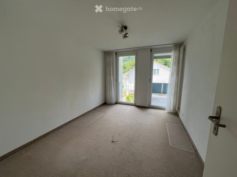 Empty room with light-colored walls, carpeted floor, and large sliding glass doors leading to a balcony.