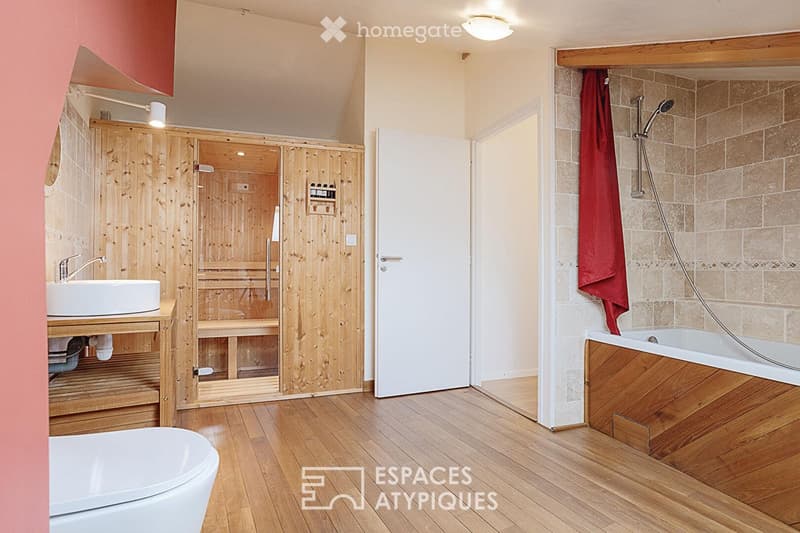 Bathroom with wooden sauna, sink, bathtub, and shower. Features wooden flooring and warm lighting.