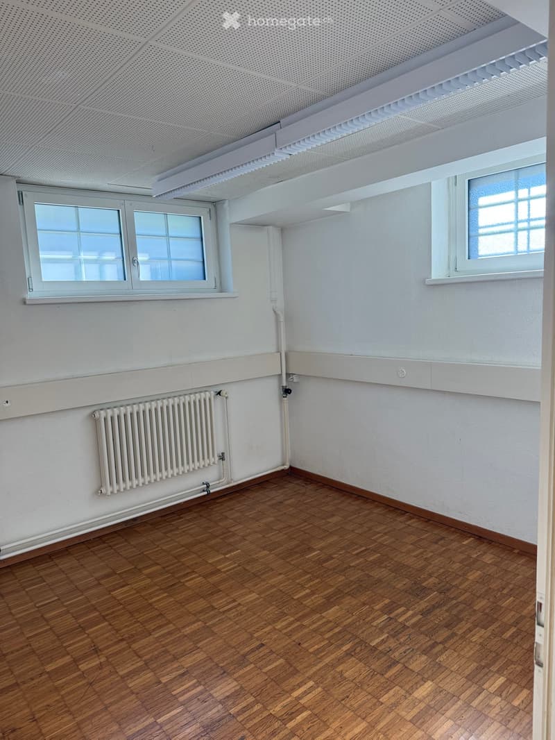 Unfurnished Room. Empty room with wooden flooring, white walls, and two windows. A radiator is mounted on one wall.