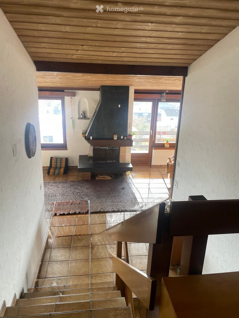 Hallway with a fireplace, wooden ceiling, tiled floor, and a staircase leading upwards.
