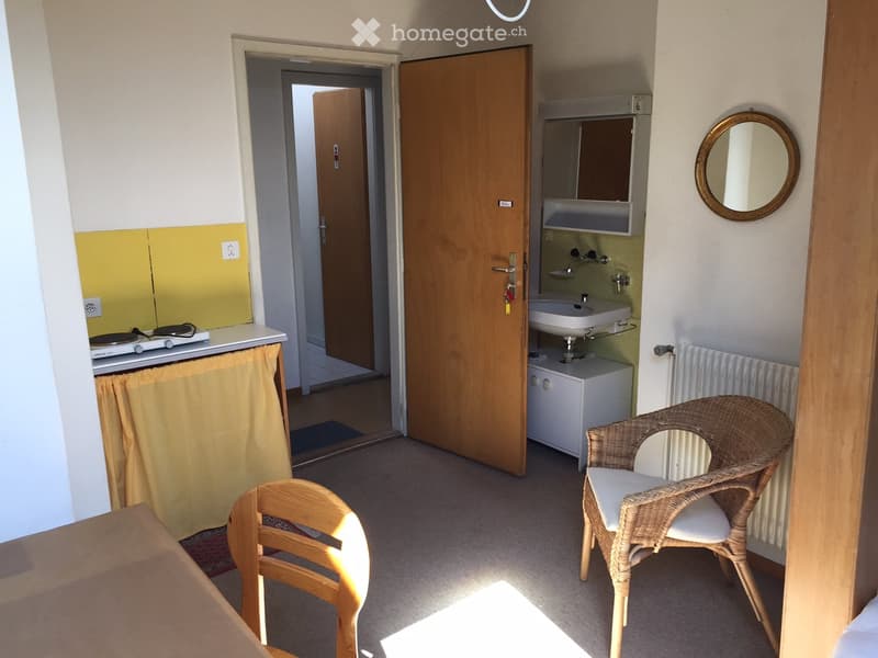 kitchen with sink, stove, sink cabinet, small wicker chair, small wood chair, radiator