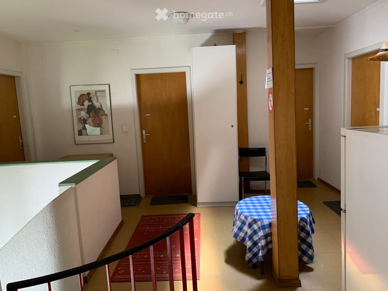 interior hallway, red carpet, blue table with white tablecloth, picture frame, wooden doors, black chair, white refrigerator
