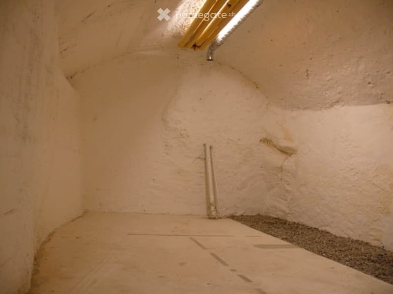 Empty room with white walls, concrete floor, pipe on the wall, small light on the ceiling