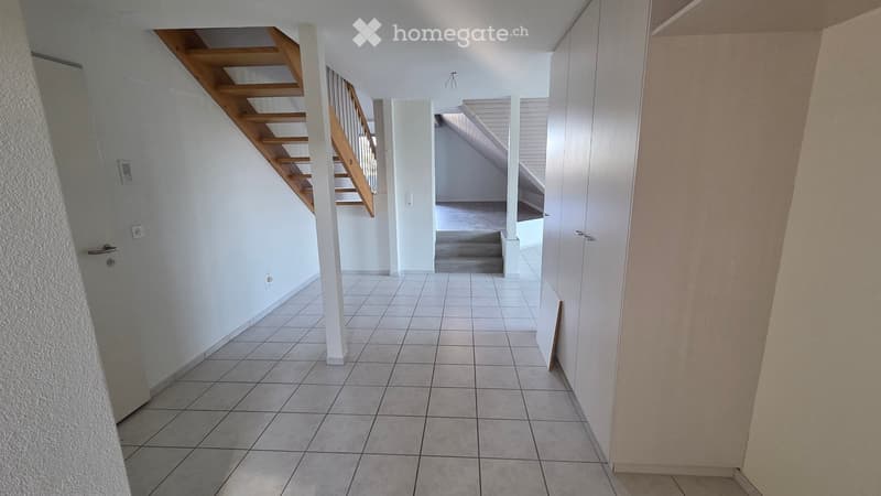 Empty hallway with tiled floor, white walls, and a staircase leading upwards.