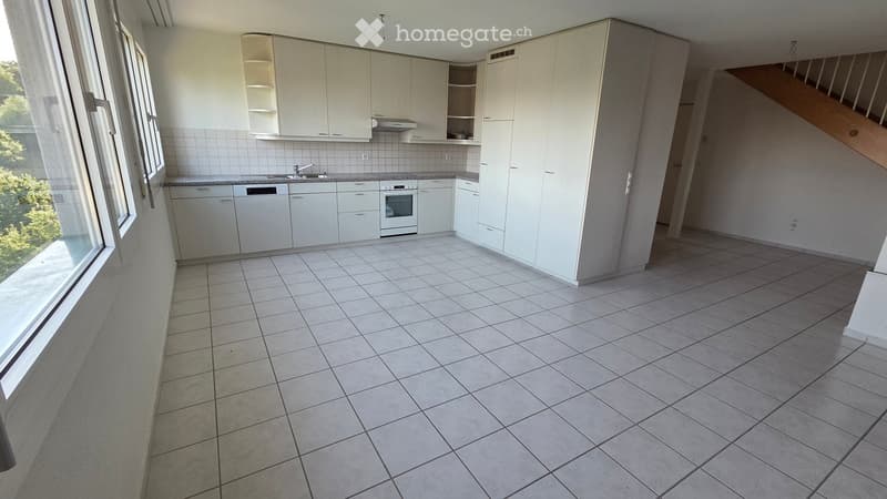 Empty kitchen with white cabinets, tiled floor, sink, oven, and dishwasher.