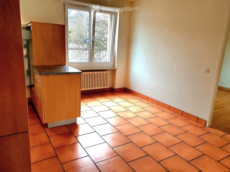 Tiled kitchen with a window and a radiator, wooden cabinet