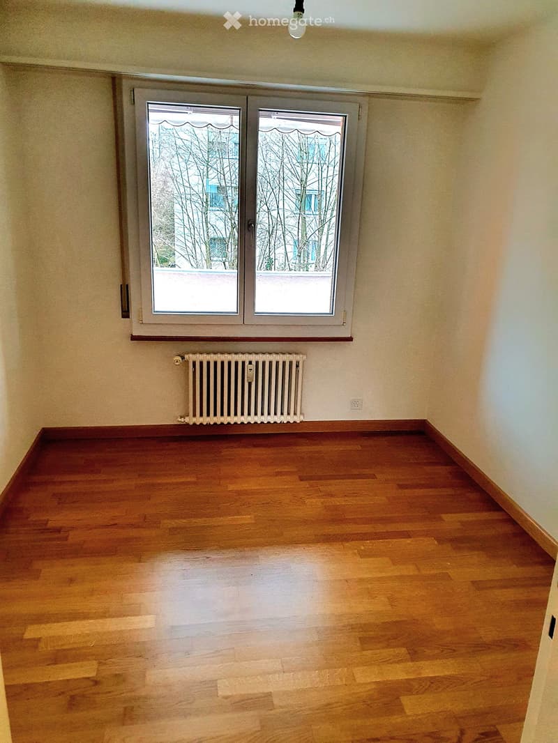 Empty room with hardwood floors, white walls, a window, and a radiator