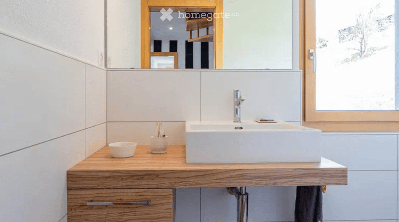 Bathroom with white sink, wooden countertop, white tiles, mirror, and wooden cabinet