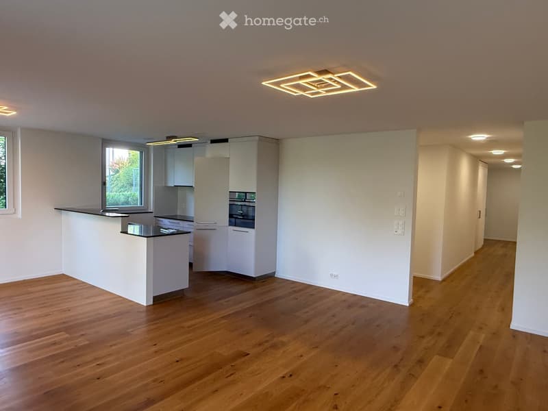 Modern kitchen with white cabinets, a kitchen island, and built-in oven, featuring wooden flooring and recessed lighting.