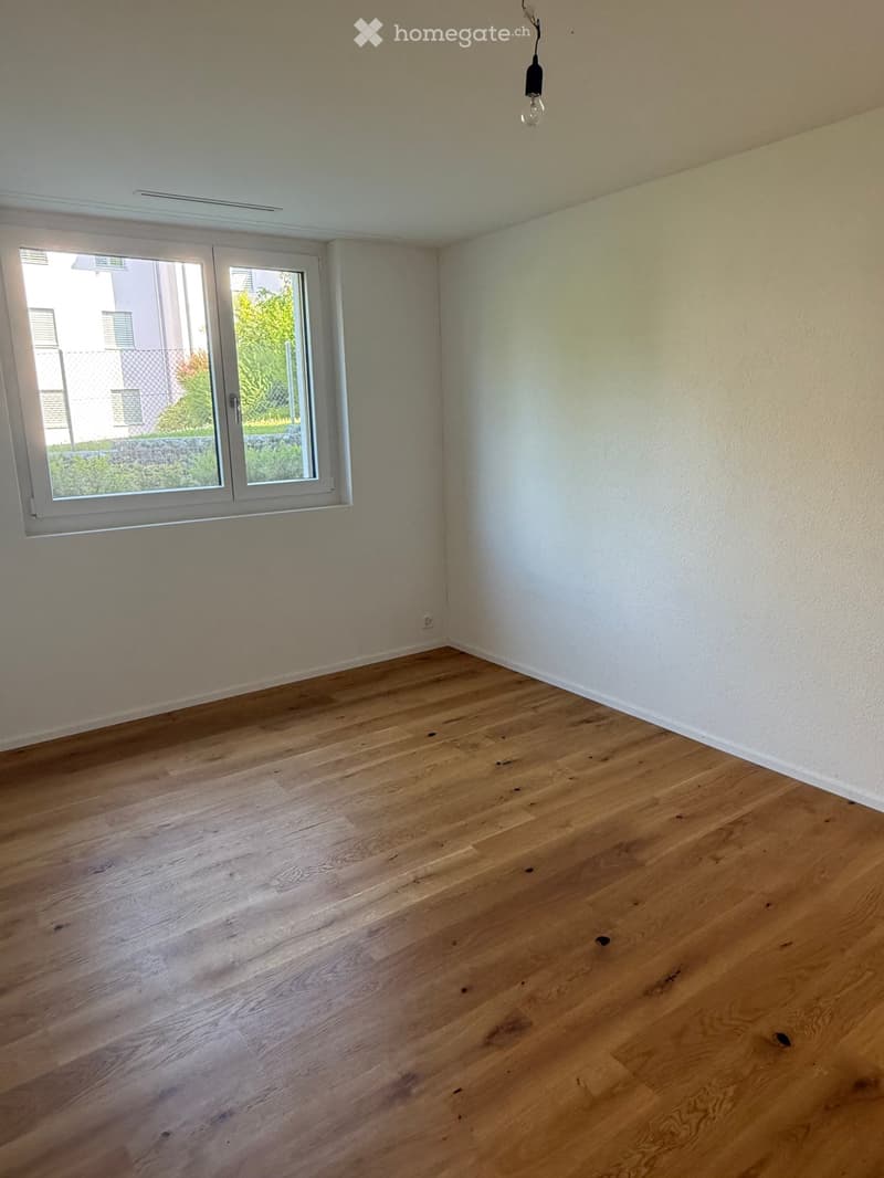 Empty room with light wooden flooring, white walls, and a single window with white frame. No furniture or equipment present.