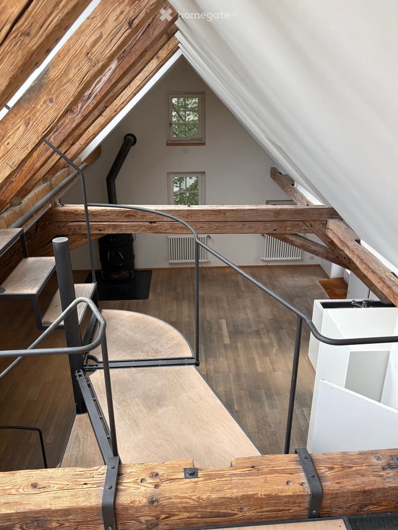 Unfurnished Room. An attic space with wooden beams, exposed wooden floor, metal staircase, and a small window. The room is empty with no furniture or furnishings.