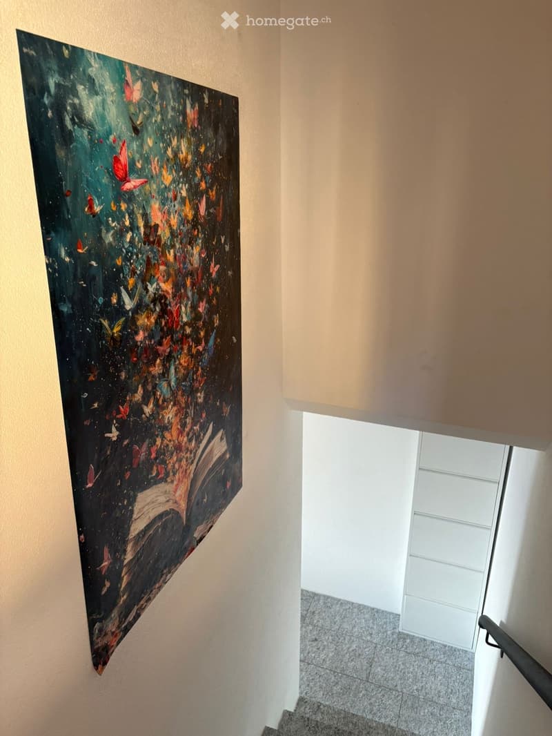 Hallway with a large abstract painting featuring butterflies on one wall, a window at the end, and a staircase leading upwards.