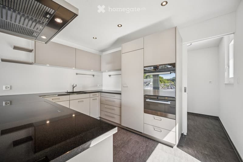 Modern kitchen with white cabinets, stainless steel appliances, and a black countertop.