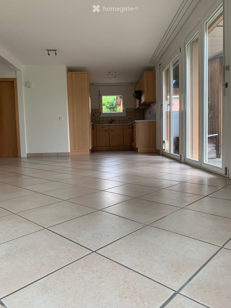 Empty room with tiled floor, wooden cabinets, and large sliding glass doors leading to an outdoor area.