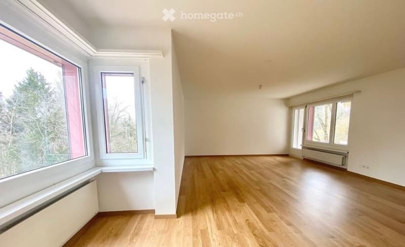 Empty room with wooden flooring, white walls, and multiple windows offering natural light. No furniture or equipment present.