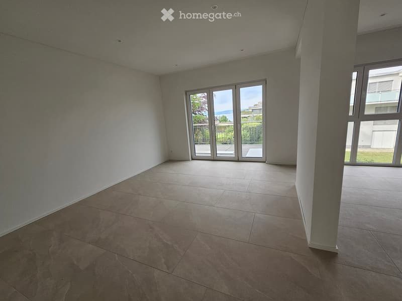 Empty room with tiled floor and white walls, featuring large sliding glass doors leading to a balcony.