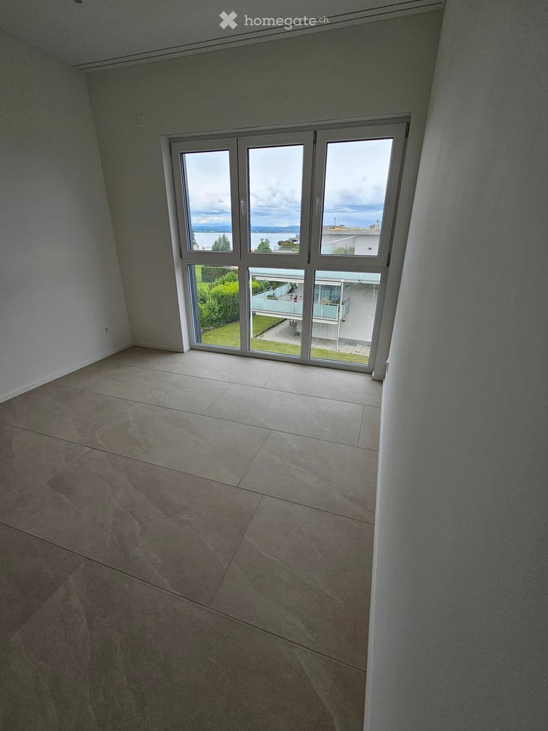 Empty room with tiled floor and large sliding glass doors leading to a balcony and outdoor area.