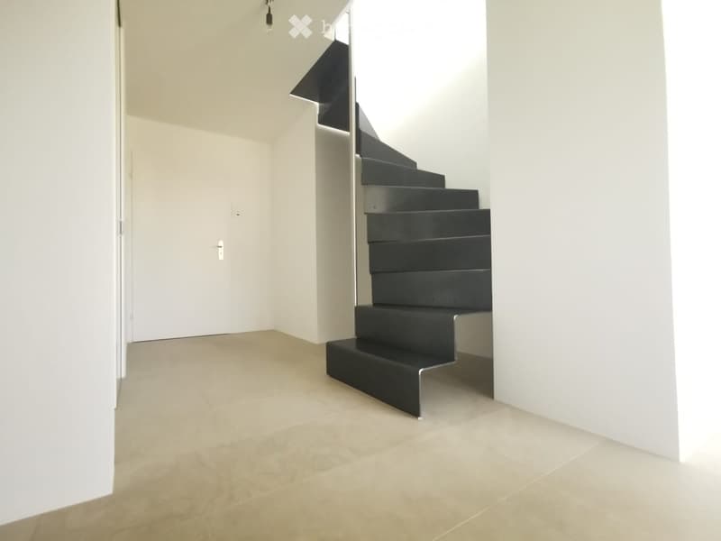 Modern hallway with a sleek black staircase, light-colored tiled floor, and white walls.