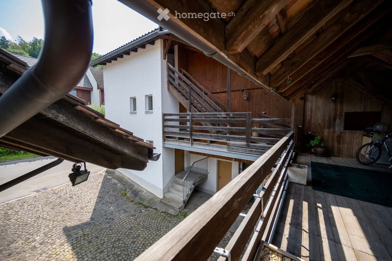 white exterior walls, wooden interior, wooden staircase, metal handrail, balcony