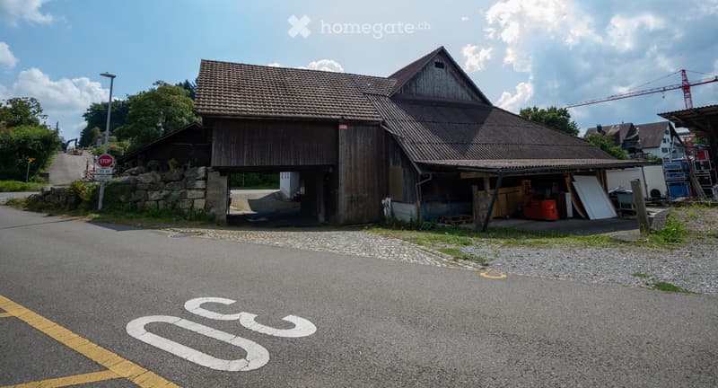 Wooden barn style house, brown roof, open garage, stone walls on one side