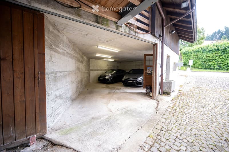two cars parked, concrete walls, wooden ceiling, lights