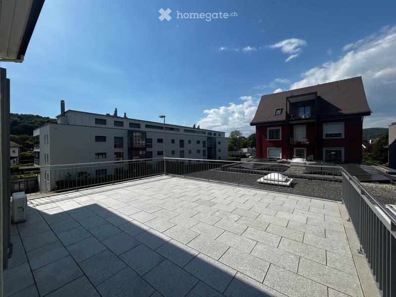 Balcony with tiled floor, metal railing, and view of surrounding buildings and greenery.