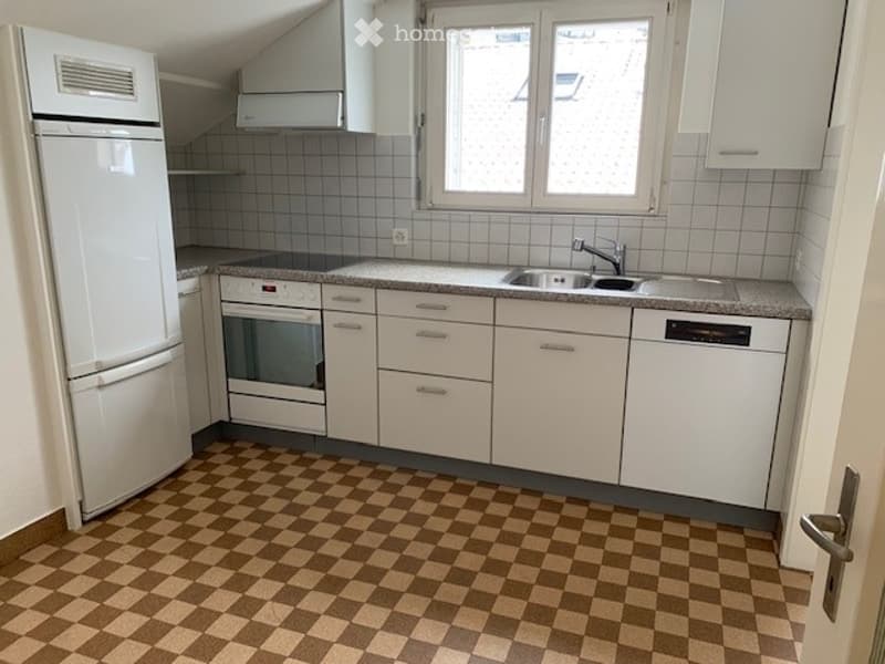 Modern kitchen with white cabinets, stainless steel appliances, and a checkered floor.