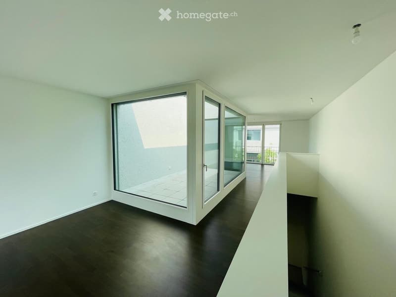 Empty room with dark wooden flooring, white walls, and large sliding glass doors leading to a balcony area.