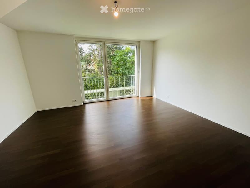 Empty room with wooden flooring, white walls, and large sliding glass doors leading to a balcony.