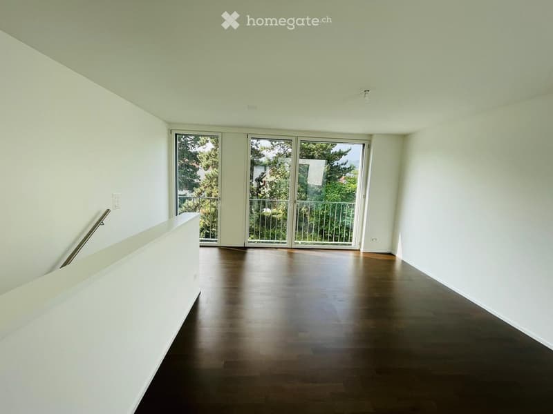 Empty room with light-colored walls, dark wooden flooring, and large sliding glass doors leading to a balcony.