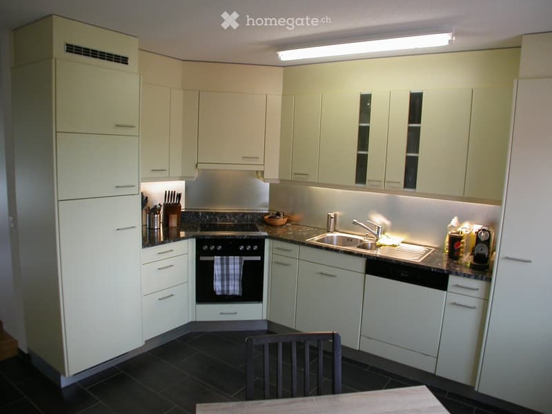 Modern kitchen with white cabinets, stainless steel appliances, granite countertops, and a black tiled floor.