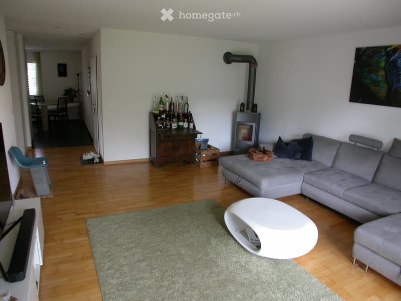 Modern living room with a grey sectional sofa, white coffee table, floor lamp, TV stand, bar cabinet, and a fireplace.