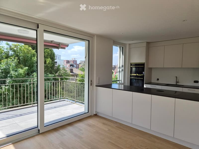 Modern kitchen with white cabinets, black countertops, and a large sliding glass door leading to a balcony.