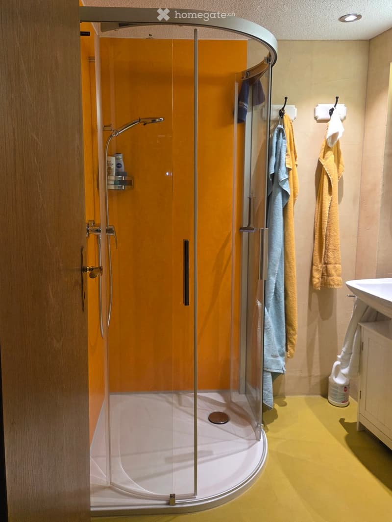 Modern bathroom with a walk-in shower, glass enclosure, towel rack, sink, and cabinet.