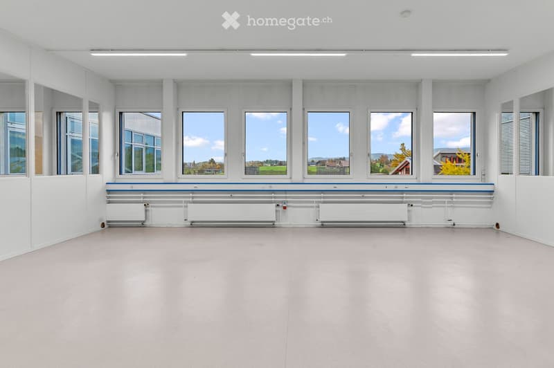 Empty room with white walls, large windows, and a radiator along the wall. No furniture or equipment is present.
