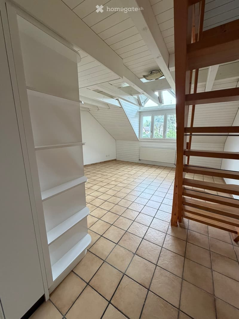 Empty hallway with tiled floor, wooden railing, and skylight window at the end.