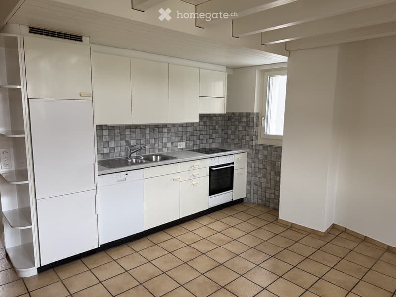 Modern kitchen with white cabinets, tiled backsplash, and stainless steel appliances including a refrigerator, dishwasher, and oven. The countertop features a sink with a faucet.