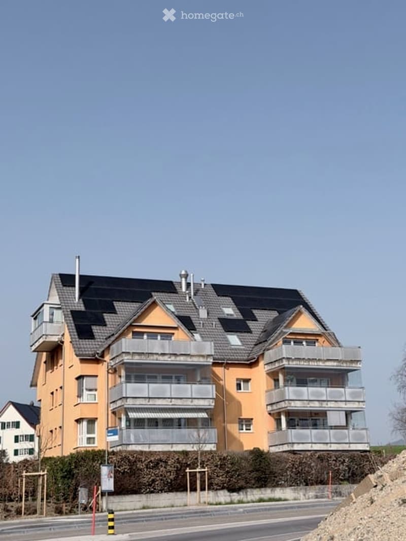 3-story building with solar panels, multiple balconies, and windows.