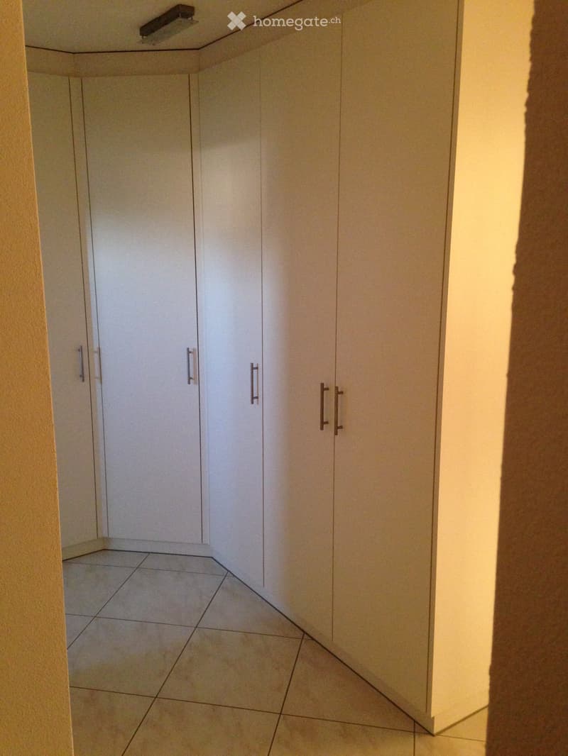 Corner cabinet in white color, tiled floor, recessed light on ceiling