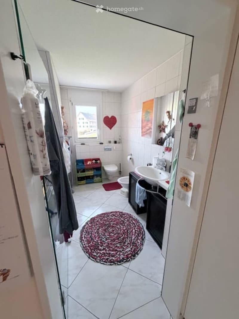 Bathroom with a sink, toilet, mirror, rug, storage box and towel