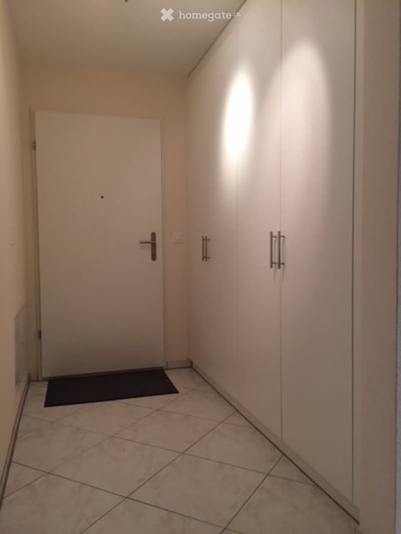 empty room with tile floor, white door, two white cabinets