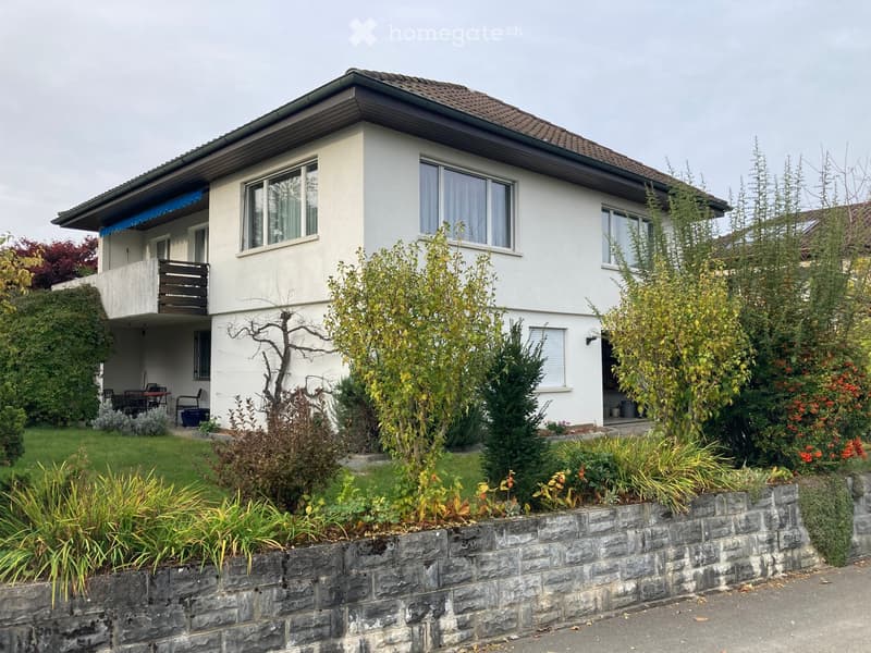 2-story house, white exterior, brown roof, balcony, garden, stone wall, outdoor seating area