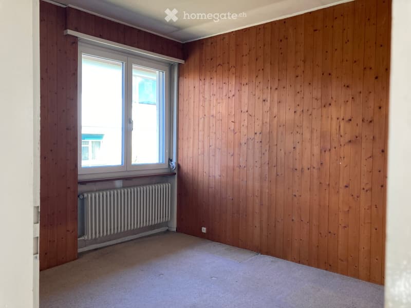 wood paneling, white radiator, carpeted floor, large window