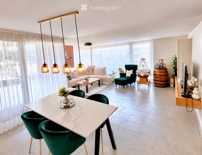 Modern living and dining area with a white sofa, coffee table, green chairs, and a marble dining table. Features large windows with sheer curtains, pendant lights, and decorative items including a barrel and a screen.