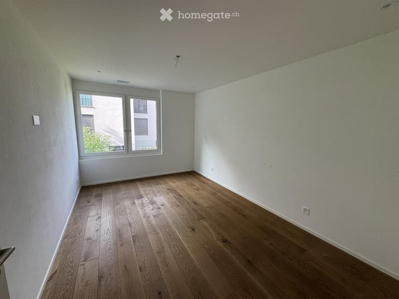 Empty room with wooden flooring and large windows, no furniture or equipment present.