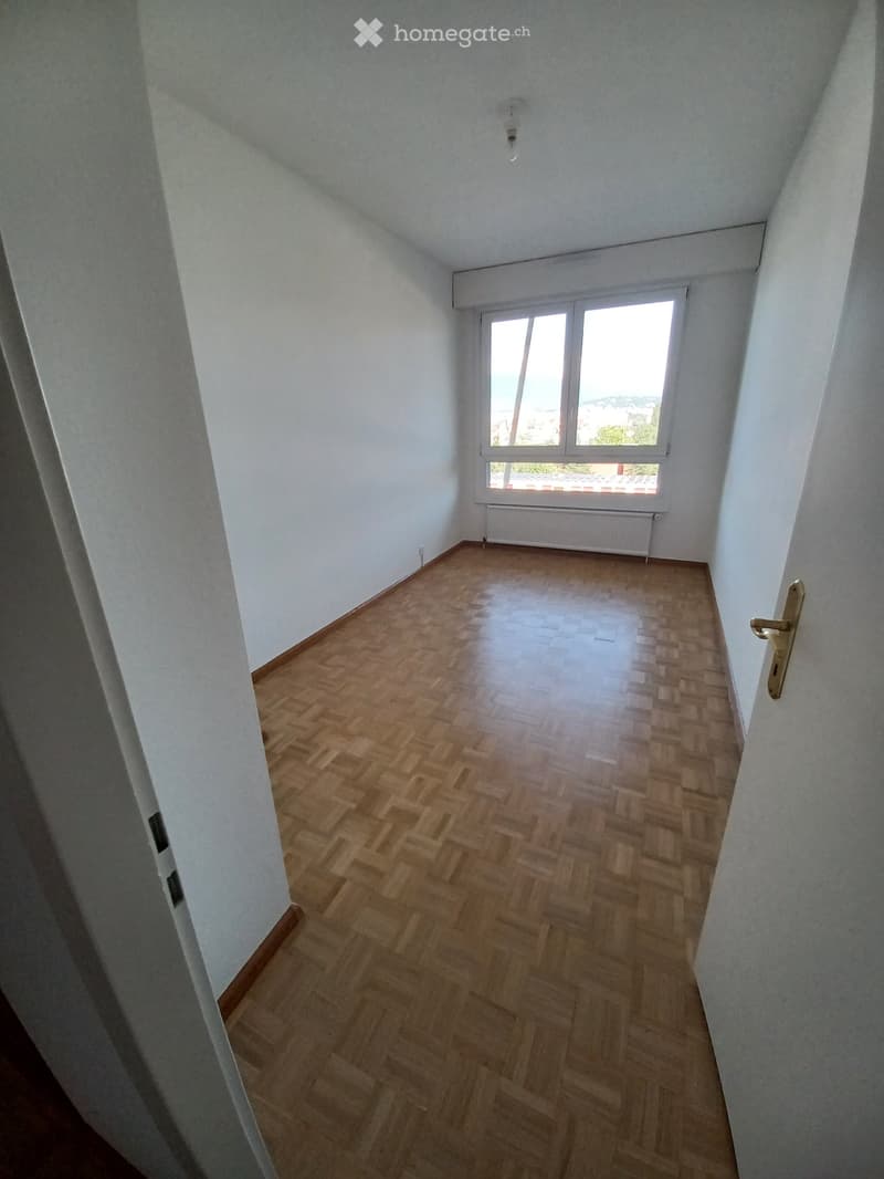 Empty room with wooden flooring, white walls, and a large window with a view. No furniture or equipment is present.
