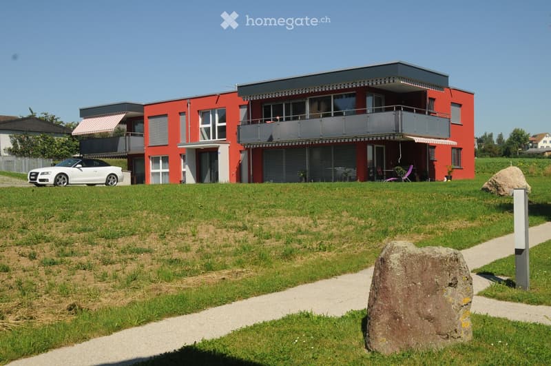 two story house, red brick, white windows, balcony, garage, car parked outside, lawn