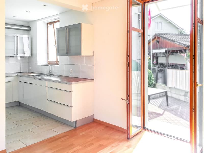 modern kitchen with white cabinets, wooden floor, stainless steel sink, large window, sliding glass door
