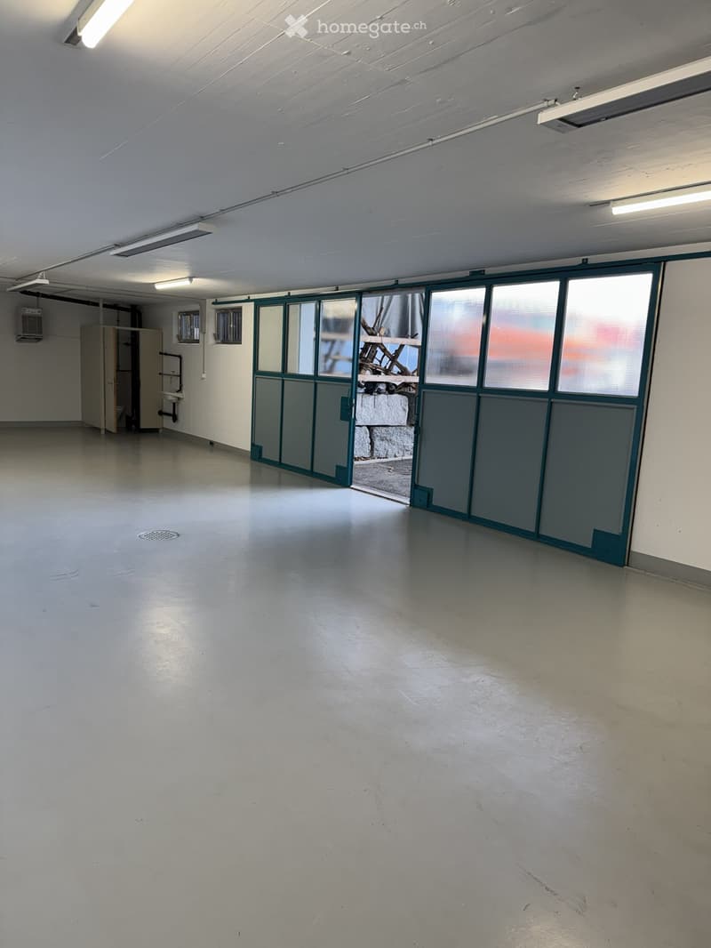 Empty room with white walls, white floor, large windows, and a door leading to an outdoor area.