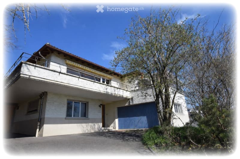 Two-story house with white exterior, blue garage door, and balcony on the upper level.